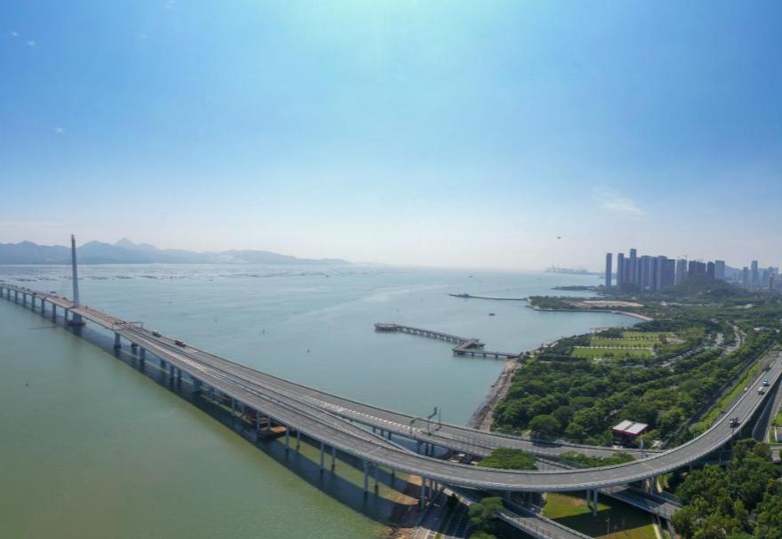 深圳湾大桥是继罗湖、皇岗和沙头角之后深圳第4条跨境通道，全长5545米，设南北两个通航桥，主跨分别为210米和180米。大桥连接深圳蛇口与香港元朗，为中国公路干线网中唯一与香港连接的高速公路大桥，也是广深沿江高速公路的咽喉。广州与香港的距离因该桥建成通车缩短至100千米。大桥深圳侧独塔斜拉桥塔采用向香港侧倾斜的斜塔，与香港侧斜拉桥的桥塔向深圳侧倾斜互相对应，寓意深港两地手牵手走向一起。图为深圳湾大桥。
