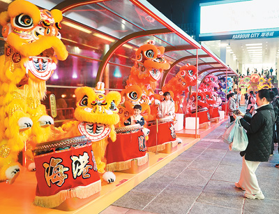 近日在香港维多利亚港畔，游客和醒狮合影。新华社记者 褚萌萌摄