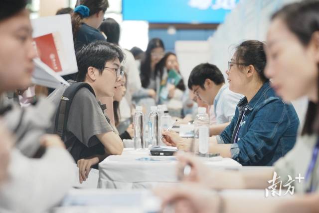 “百万英才汇南粤”武汉招聘会现场火爆，企业招聘展位座无虚席，面试洽谈对接需求。